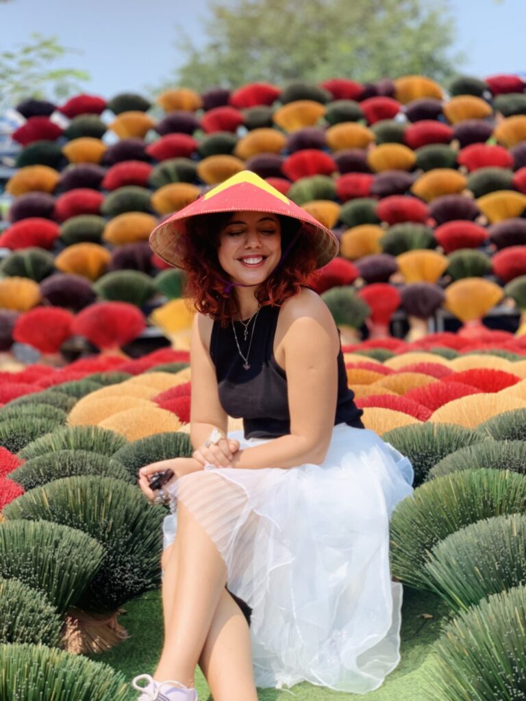 Traveler posing among colorful incense bundles at a Vietnamese incense village