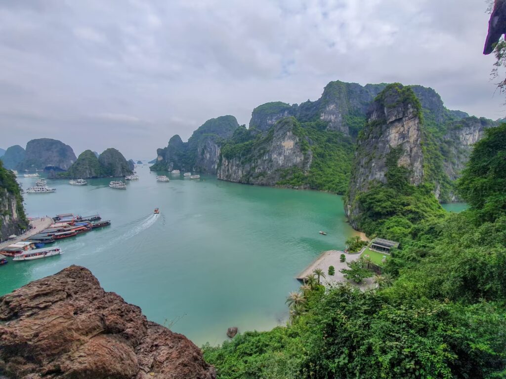 Scenic viewpoint overlooking Ha Long Bay with cliffs and boats.
