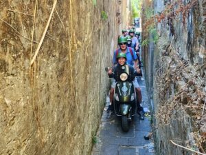 Locals riding motorbikes through a narrow alley in Hanoi.
