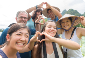 Diverse group of travelers smiling and making a heart shape on a tailor-made tour in Vietnam