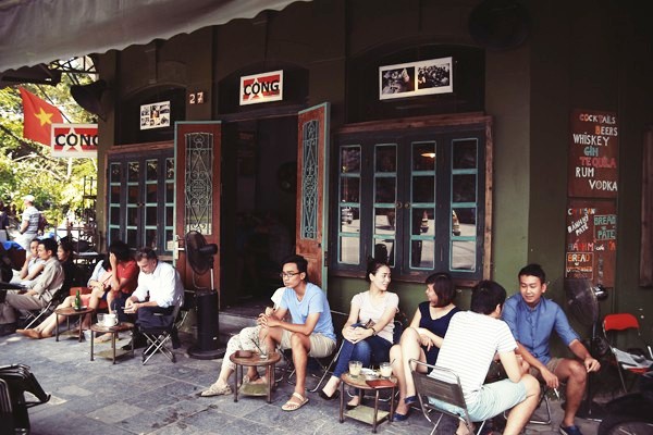 A group of friends chatting in front of a traditional Vietnamese coffee shop.