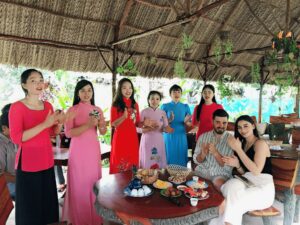 Vietnamese family and guests enjoying a traditional meal together in a countryside setting.