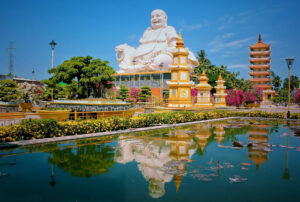 White Buddha statue and a lakeside pagoda in Vietnam, reflecting traditional Buddhist culture.