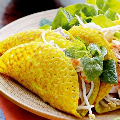 Vietnamese bánh xèo crispy pancake served with herbs and fresh vegetables.