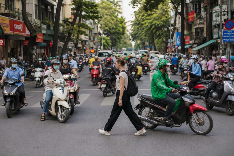 Tourist crossing a busy street filled with motorbikes in Vietnam