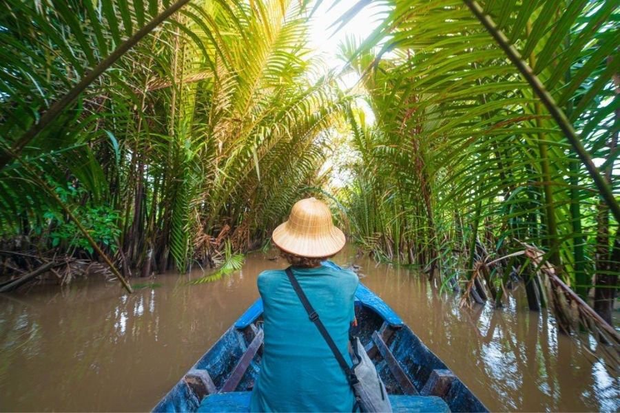 Travelers exploring peaceful waterways of the Mekong Delta by traditional boat
