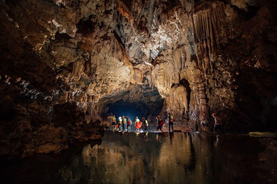 Adventure travelers exploring underground rivers in the Tu Lan Cave System Vietnam
